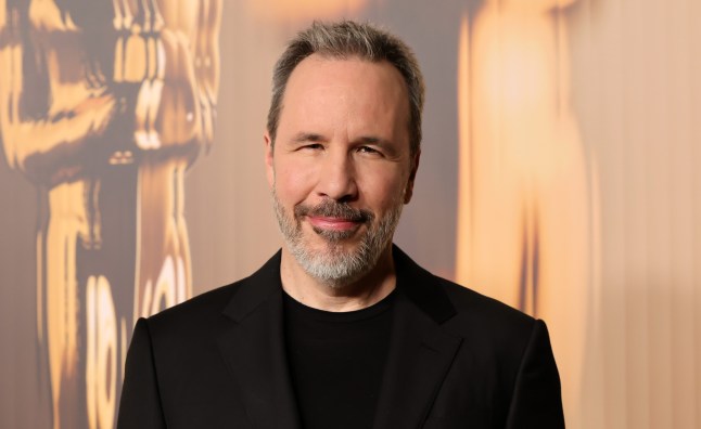 Denis Villeneuve at the Oscars, wearing a black suit and smiling